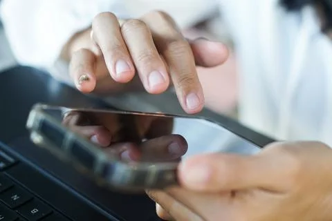 Hands using smartphone over laptop keyboard Foto stock