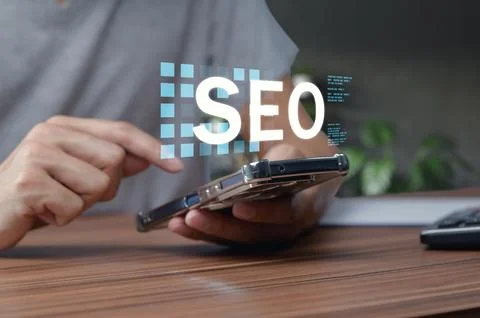 Hands Using Smartphone with SEO Concept on Wooden Desk Background Stock Photos