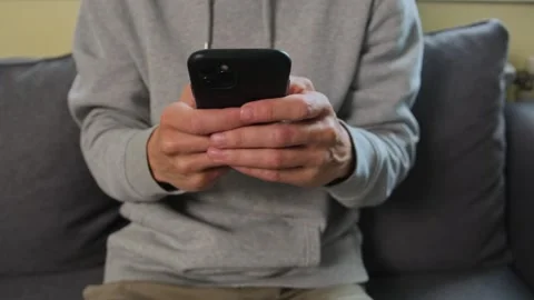 Hands using smartphone on sofa close up social media messaging. Stock Footage 315118878