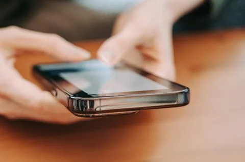 Hands Using Smartphone on Wooden Table Close-Up Stock Photos