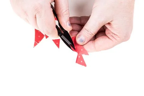 Hands using snipper tool to cut pattern out of red paper Stockfoto's