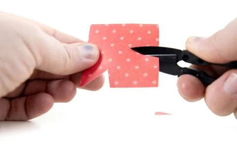 Hands using snipper tool to cut exact pieces out of red paper Stock Photos
