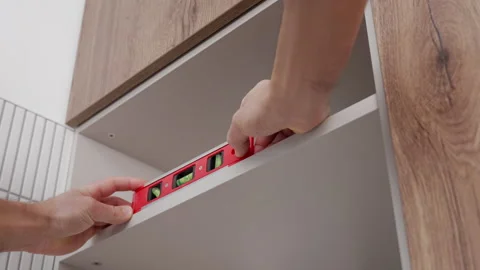Hands using spirit level to align cabinet shelf during kitchen installation Stock Footage 329482124