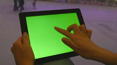 Hands using tablet pc with green screen. People skate on ice rink at background Stock Footage 64229596