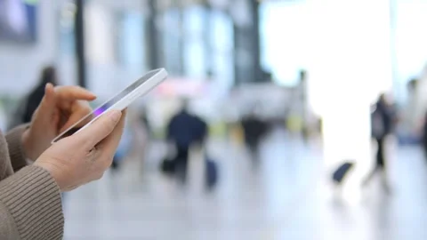 Hands using tablet while walking through crowded terminal 库存影片 340907769