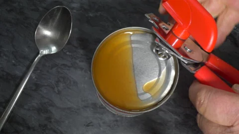 Hands using a tin opener to remove the lid from a can of red grapefruit. Stock Footage 139451566