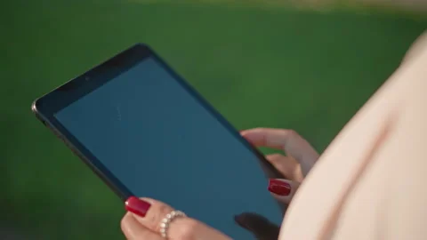 Hands using touchscreen tablet outdoors with fingertip taps and swipes, red Stock Footage 346625605