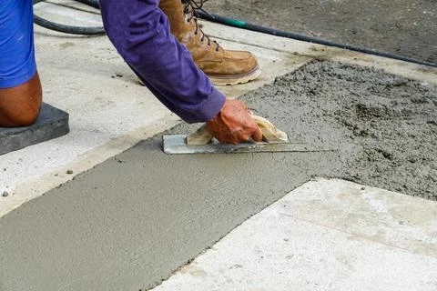 Hands using a trowel to smooth fresh wet concrete Stock Photos