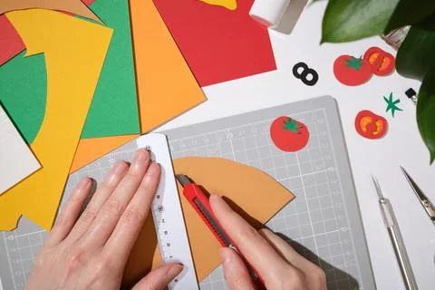 Hands using a utility knife to cut beige paper sheet on a gray mat. DIY craft 스톡 사진