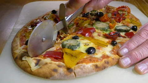 Hands using a wheel tool to cut a pizza in half. Stock Footage 144929142