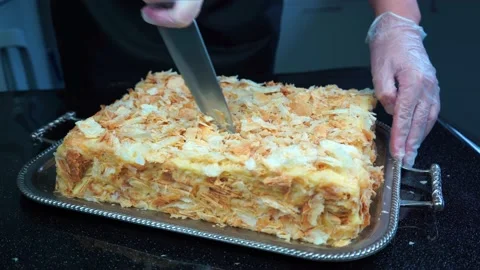 Hands in vinyl gloves cutting knife cream puff cake Napoleon, sprinkled crumbs Stock Footage 159092852