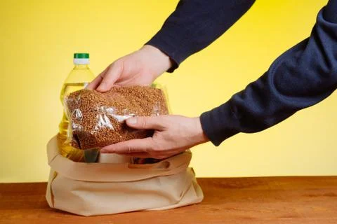 The hands of the volunteer put the basic necessities in a bag for donations t Stock Photos