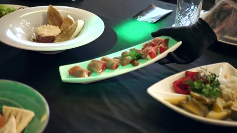 The hands of the waiter put a plate of appetizers and on the banquet table. Stock Footage 302257908