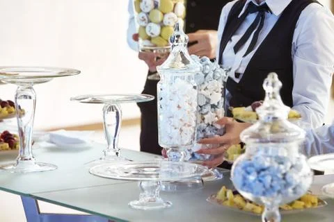 The hands of the waiters putting sweets on the table 스톡 사진