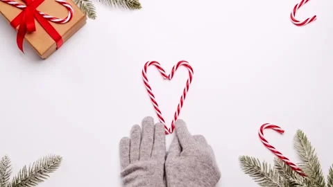 Hands in warm knitted gloves makes a heart out of Christmas candies cane Stock Footage 144657980