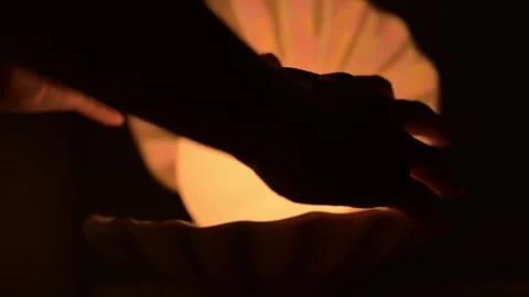 Hands warming over illuminated seashell on black background Видео 309005780