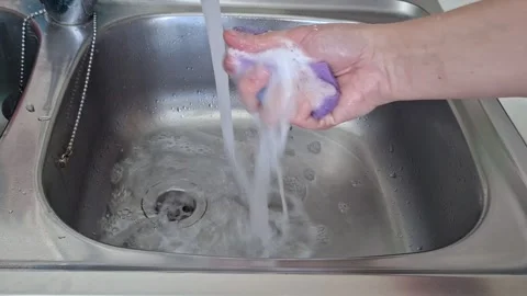 Hands wash a bar of soap under running water in a kitchen sink Stock Footage 344665023