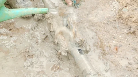 Hands wash the drill bit from clay with the help of a watering can 스톡 동영상 105675503