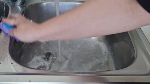 Hands wash a sponge with soap under running water in a kitchen sink Stock Footage 342720391