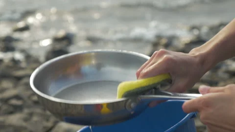 Hands washes a stove with her sponge in the wilderness, in New Zealand Stock Footage 217401842