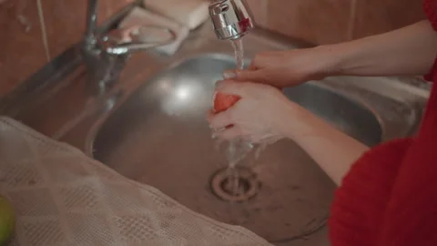 Hands washing carrot under running tap in stainless steel kitchen sink, close-up Stock Footage 346641769