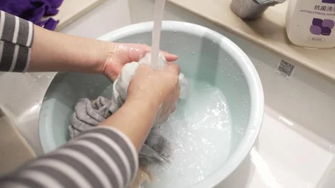 Hands Washing Clothes in Basin Under Running Tap, Close-up Shot Video stock 337413610
