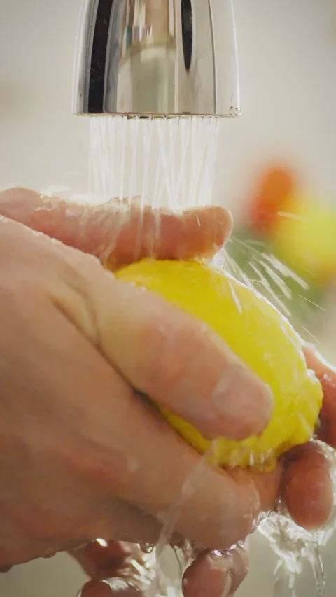 Hands washing fresh lemon under water at home kitchen faucet Stock Footage 331592899