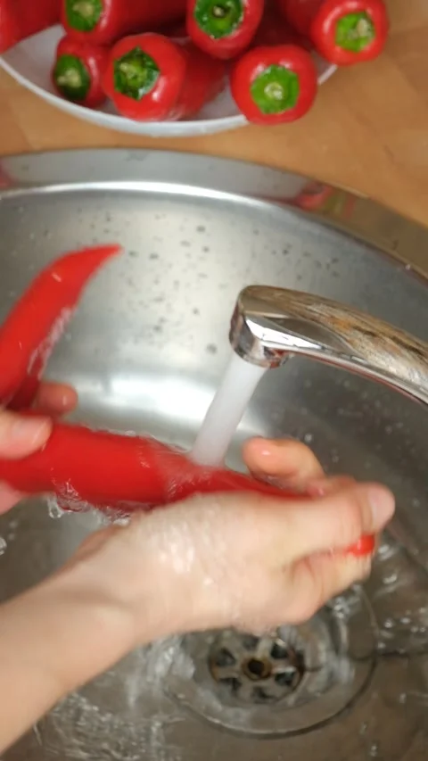 Hands washing fresh red bell peppers under kitchen faucet water stream Stock Footage 341400053