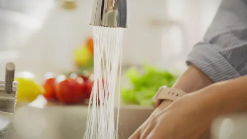 Hands washing fresh vegetables under running water in a bright modern kitche Stock Footage 291425531