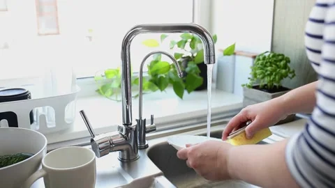 Hands washing plate with sponge, soap in kitchen in sink under running water Stock Footage 158915901
