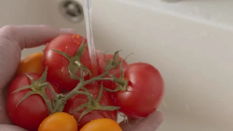 Hands washing tomatoes under running water in the white sink. Healthy eating Video stock 145016376