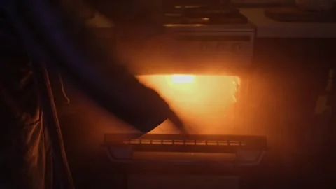 Hands waving through thick smoke rising from an oven in a kitchen, creating a Stock Footage 307756101