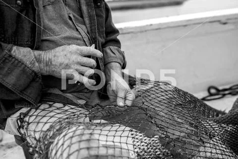 Hands of weathered fisherman mending net Stock Photos