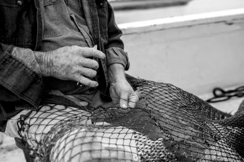 Hands of weathered fisherman mending net Stock Photos