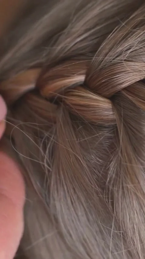 Hands weaving a complex braid on blonde hair Video stock 334168596