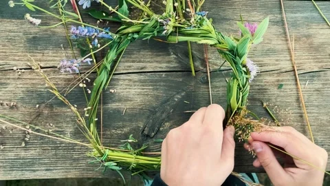 Hands Weaving Wildflower Wreath on Rustic Wooden Table Vídeos de archivo 339078032