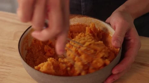 Hands whisking mashed carrot vegetable mixture in bowl during home cooking Vidéo 332771737