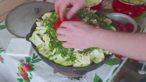 Hands of white cook puts tomatoes on cut vegitables in large cooking pot with Stock Footage 76371371