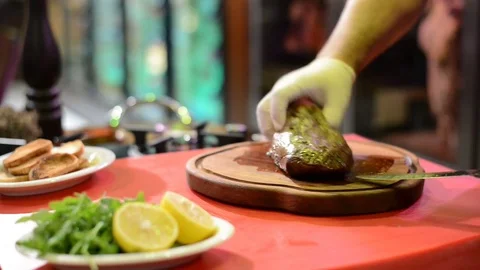 Hands in white gloves cut meat on wooden kitchen board. Stock Footage 81689994