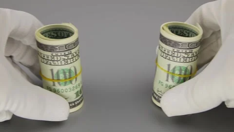 Hands in white gloves move 2 rolled rolls of 100 dollar banknotes. Close-up 스톡 동영상 142588708