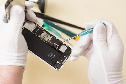 Hands in white gloves with a small screwdriver disassemble smartphone Foto stock