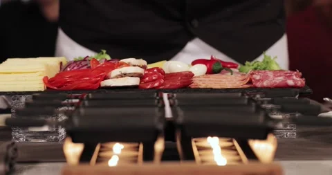 Hands in white mittens put on table tray with ingredients for raclette products Stock Footage 179026621