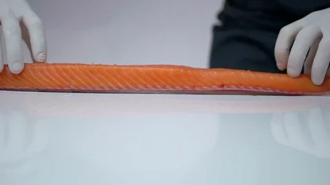 The hands in the white rubber gloves of the chef raise the red fish fillets. Stock Footage 77735712