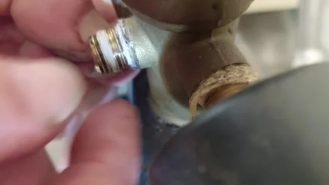 Hands winding sealing PTFE thread tape onto brass plumbing valve fitting thread Stock Footage 348568975