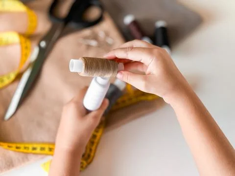 Hands winding thread for sewing crafts with scissors and fabric in background Stock Photos