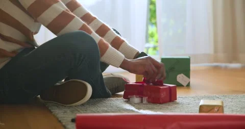 Hands by window are tightening red bow, placing gold box, labeling gifts for Stock Footage 343889097