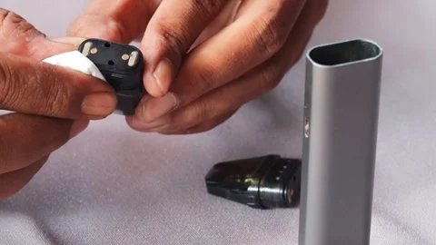 Hands wiping and cleaning reusable vape pod Stock Footage 340199800