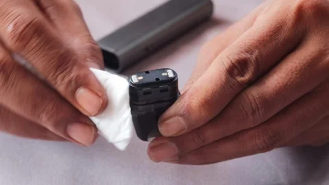 Hands wiping and cleaning reusable vape pod Stock Footage 340199804