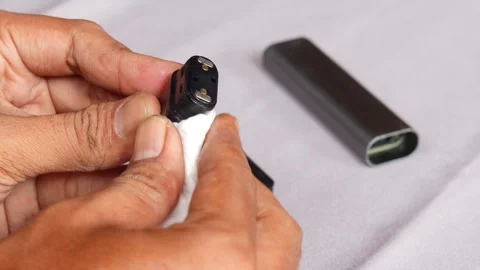 Hands wiping and cleaning reusable vape pod Stock Footage 340199806