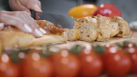 Hands of woman cutting bread on table with vegetables Stock Footage 100031191